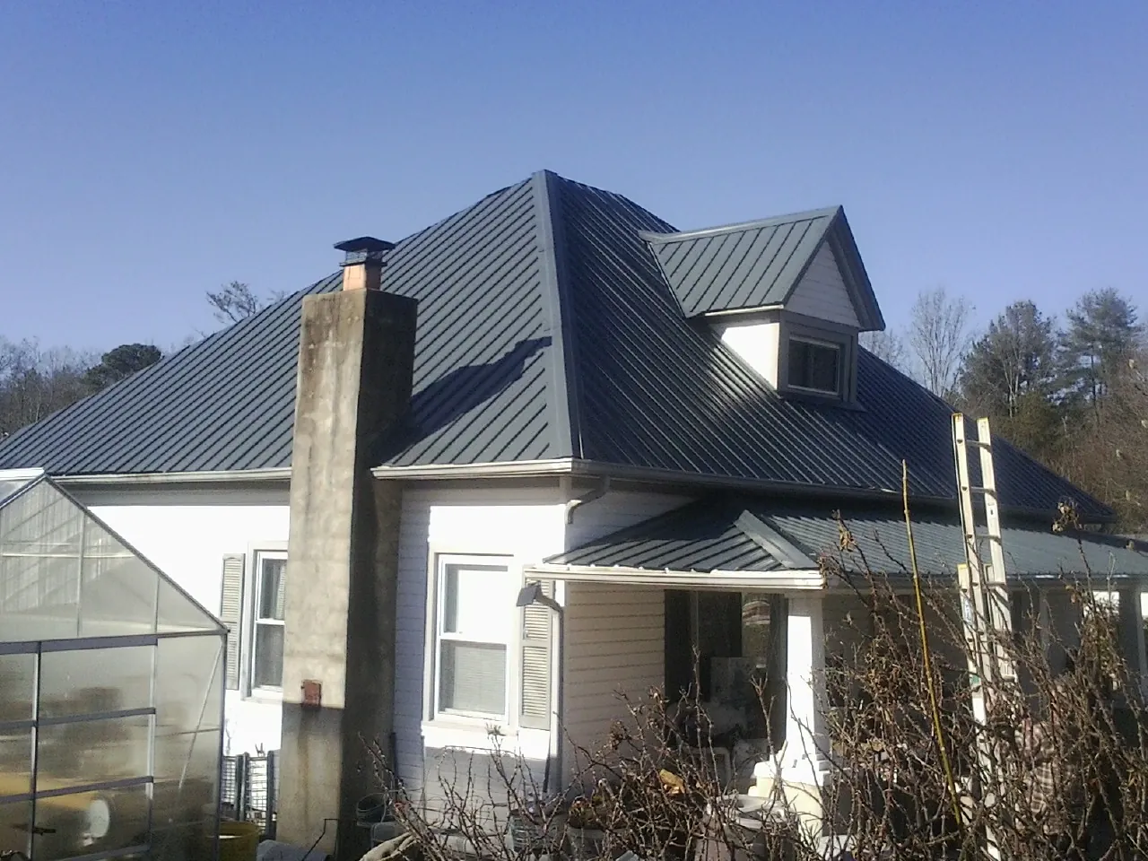 Dark blue standing seam metal roof on a white farmhouse with dormer — Slate & Tile Roof Repair by Roofing Brothers in Manheim