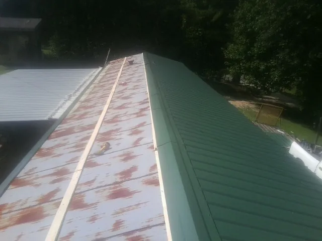 Old rusted panels beside newly installed green metal roofing — Wind Damage Roof Repair by Roofing Brothers in Manheim