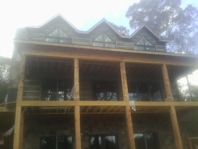 Dormers and porch framing on a large log home under construction — Roof Coating work by our crew in Manheim
