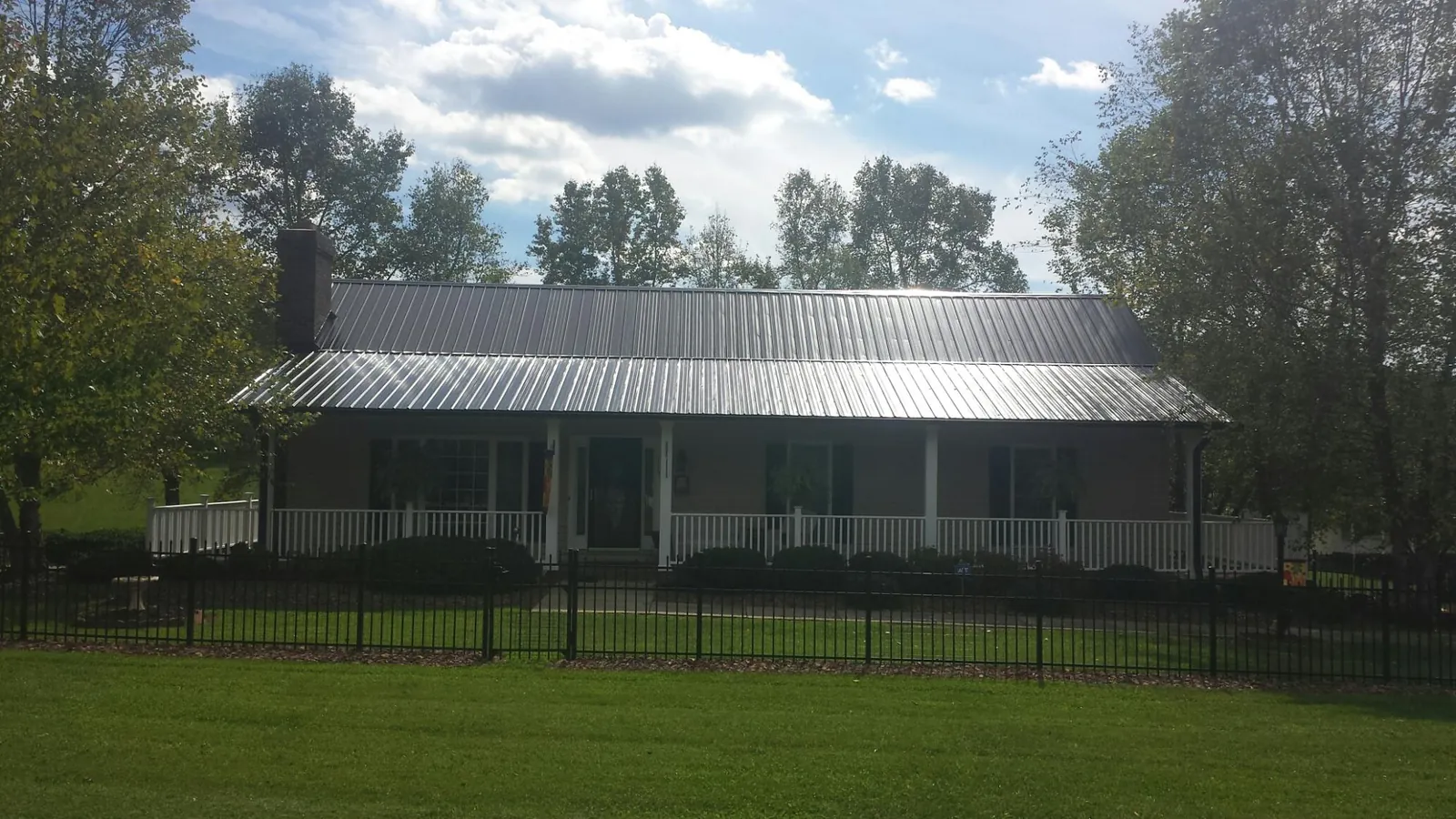 Gray metal roof on a brick ranch with a full width front porch — Gutter Guard Installation work by our crew in Manheim