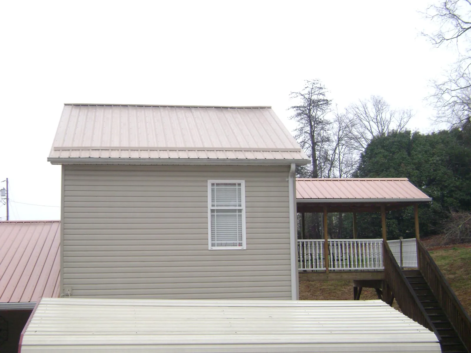 Tan metal roofs on a two story addition and attached porch, from a Roof Replacement job in Manheim