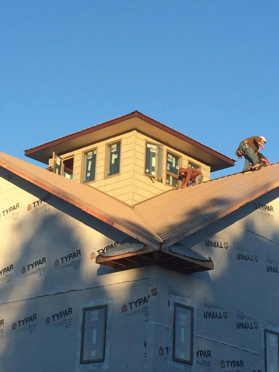 Roofers working around a rooftop cupola on a new metal roof at sunset — Roof Waterproofing in Manheim by Roofing Brothers